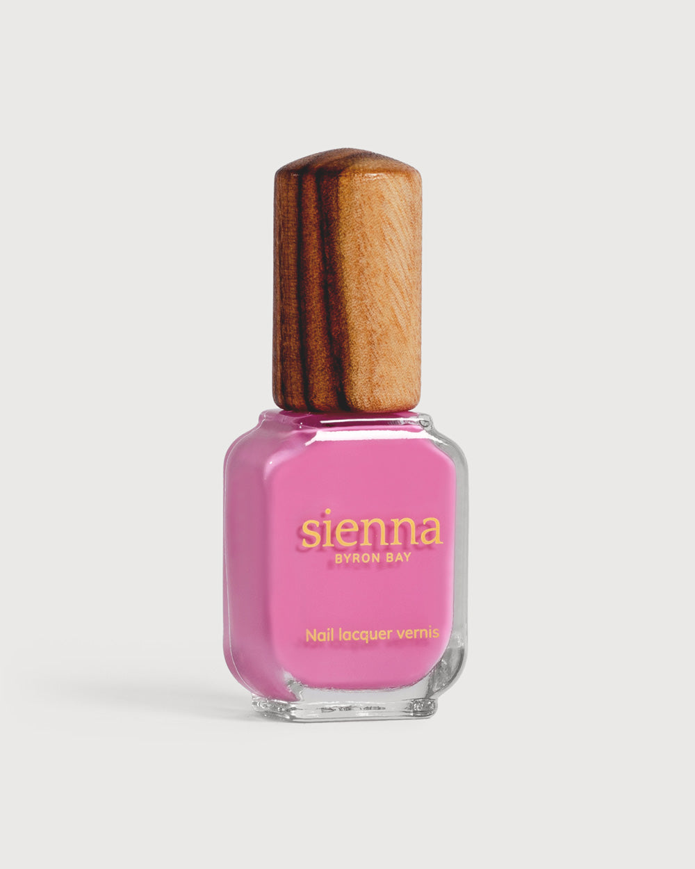 Bright mid-tone fuchsia nail polish glass bottle with timber cap