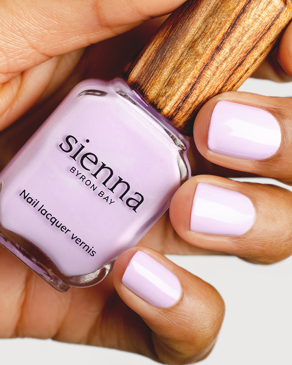 lilac purple nail polish hand swatch on medium skin tone holding a sienna bottle