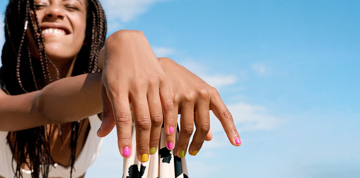 Young woman holding an umbrella wearing multi coloured nail polish by sienna
