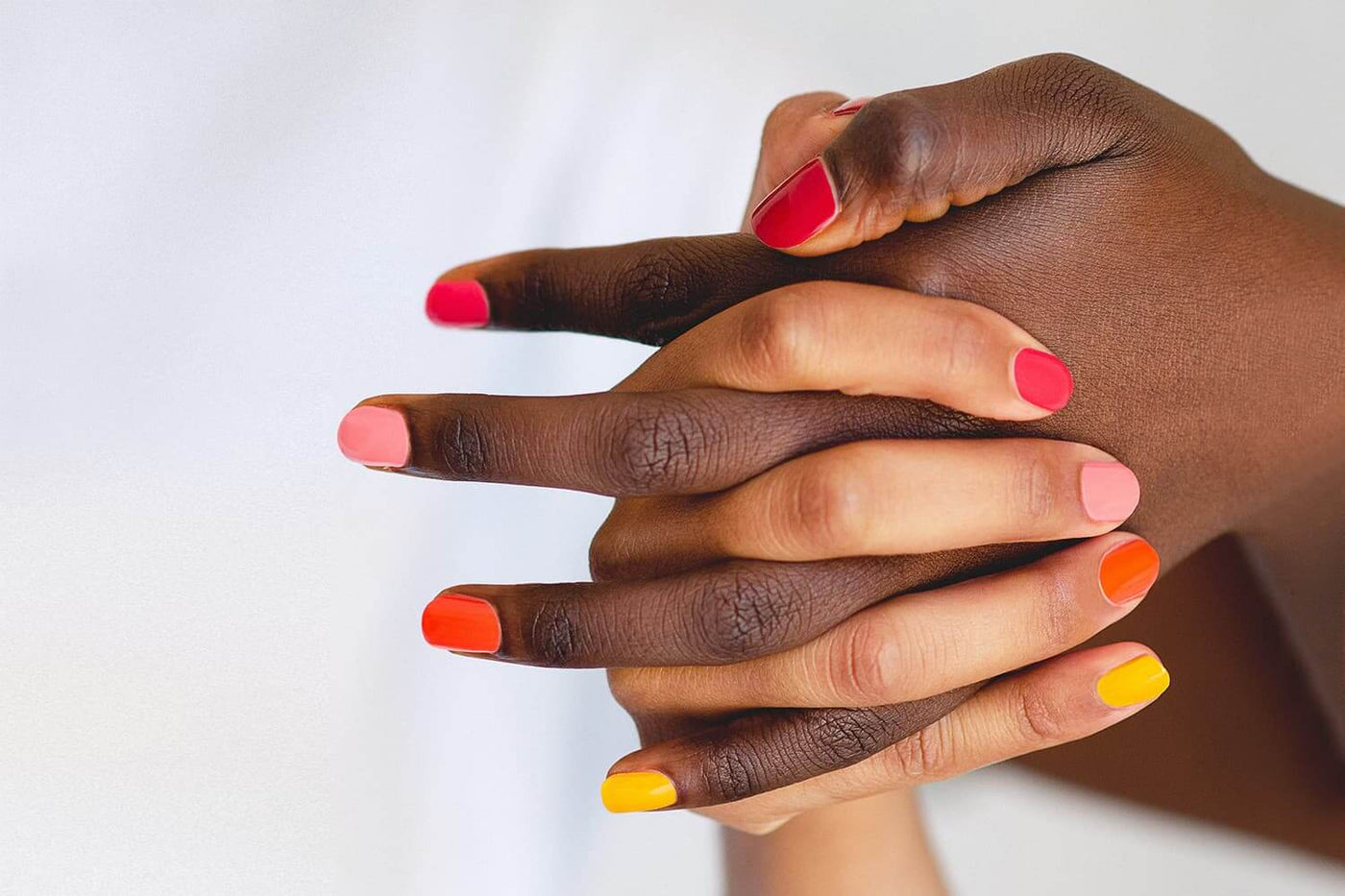 Ombre nail art with orange yellow pink and red nail polish on dark skin tone by sienna