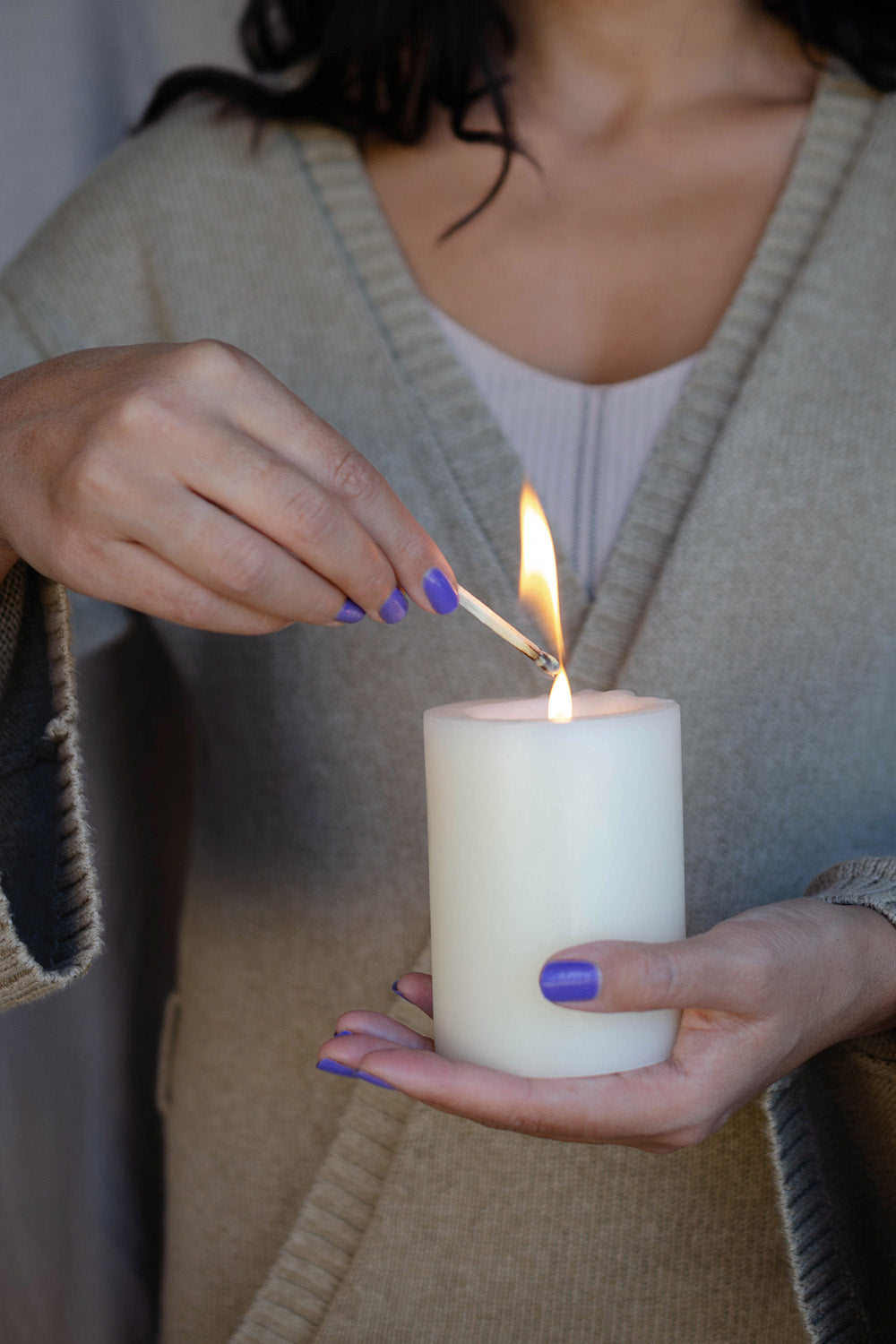Gentle Blue Lilac Crème nail polish by Sienna Byron Bay on medium skin tone hand lighting a candle.