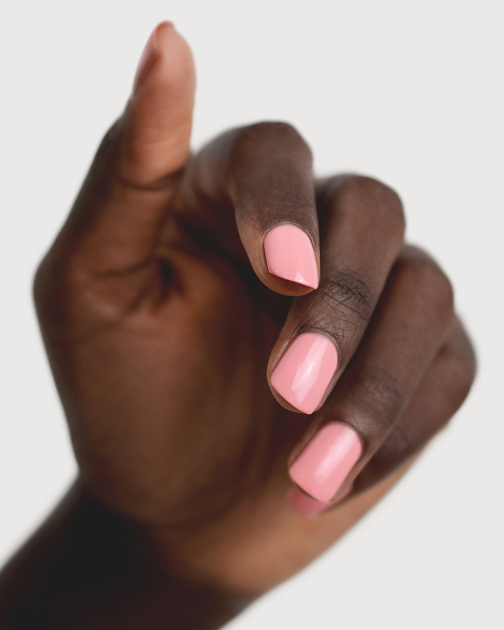 peachy pink nail polish hand swatch on dark skin tone