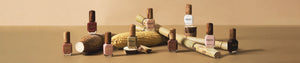Plant based ingredients cassava, corn, sugar cane layed on brown background with Sienna nail polish bottles scattered across image.