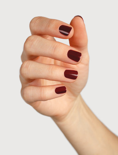 Organic mid-tone red nail polish hand swatch on fair skin tone