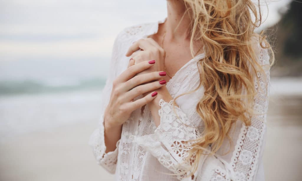 blond woman posing her hand on her shoulder and wearing raspberry pink nail polish by sienna