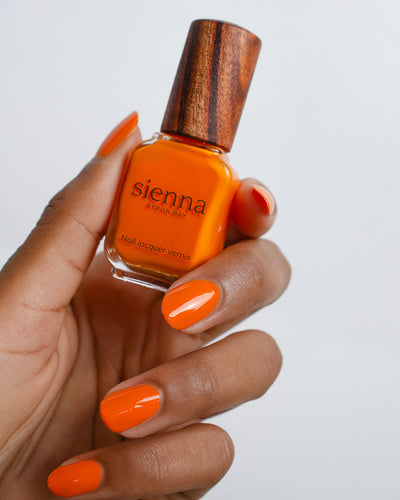 Bright papaya Orange nail polish swatch on medium skin tone by Sienna Byron Bay
