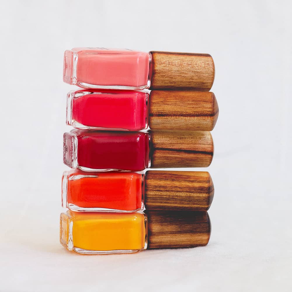 bright pink orange red and yellow nail polish stack in glass bottle with timber cap by sienna