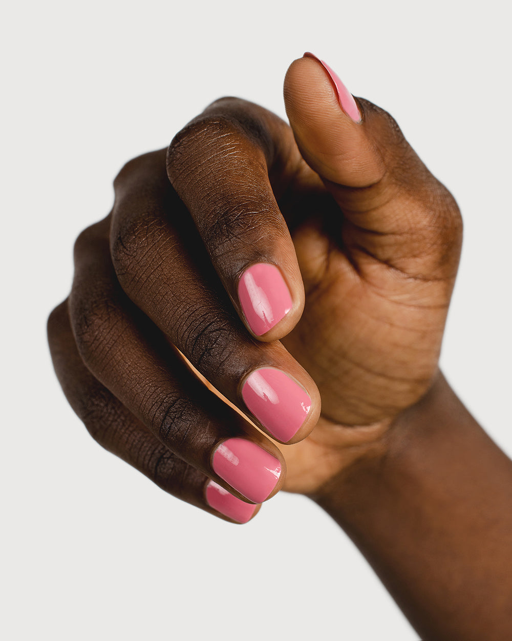 midtone pink nail polish hand swatch on dark skin tone