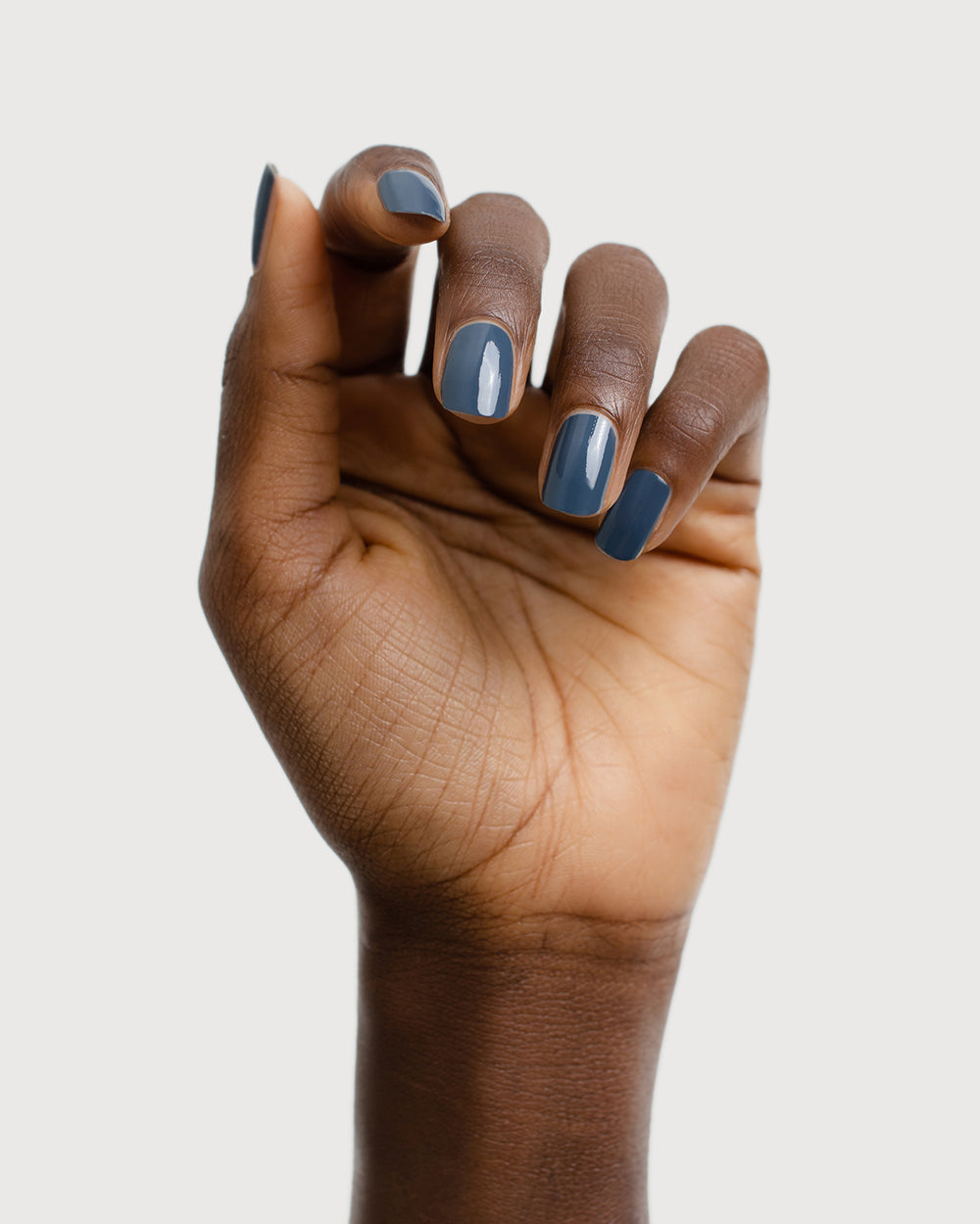 blue-grey nail polish hand swatch on dark skin tone