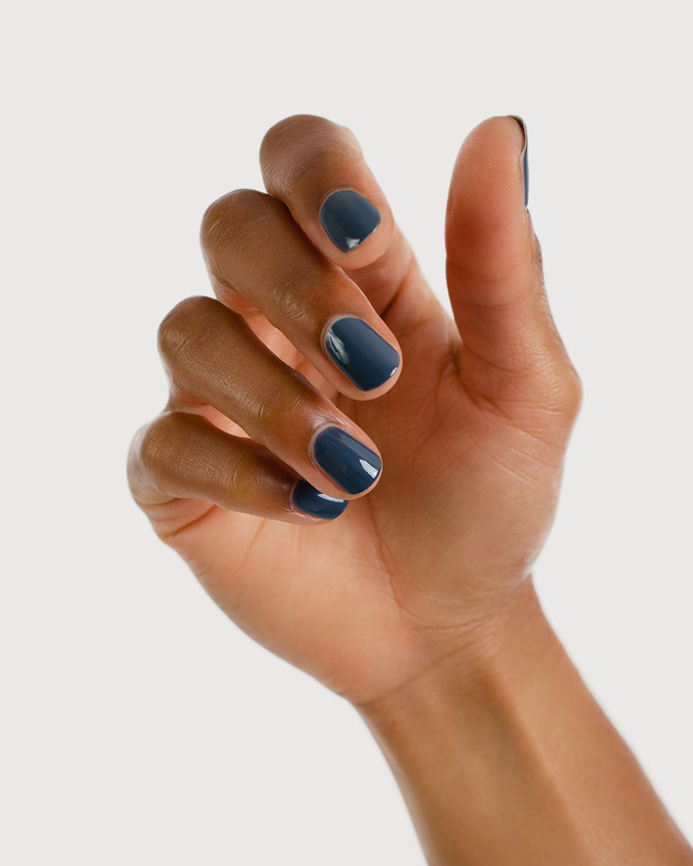 blue-grey nail polish hand swatch on medium skin tone