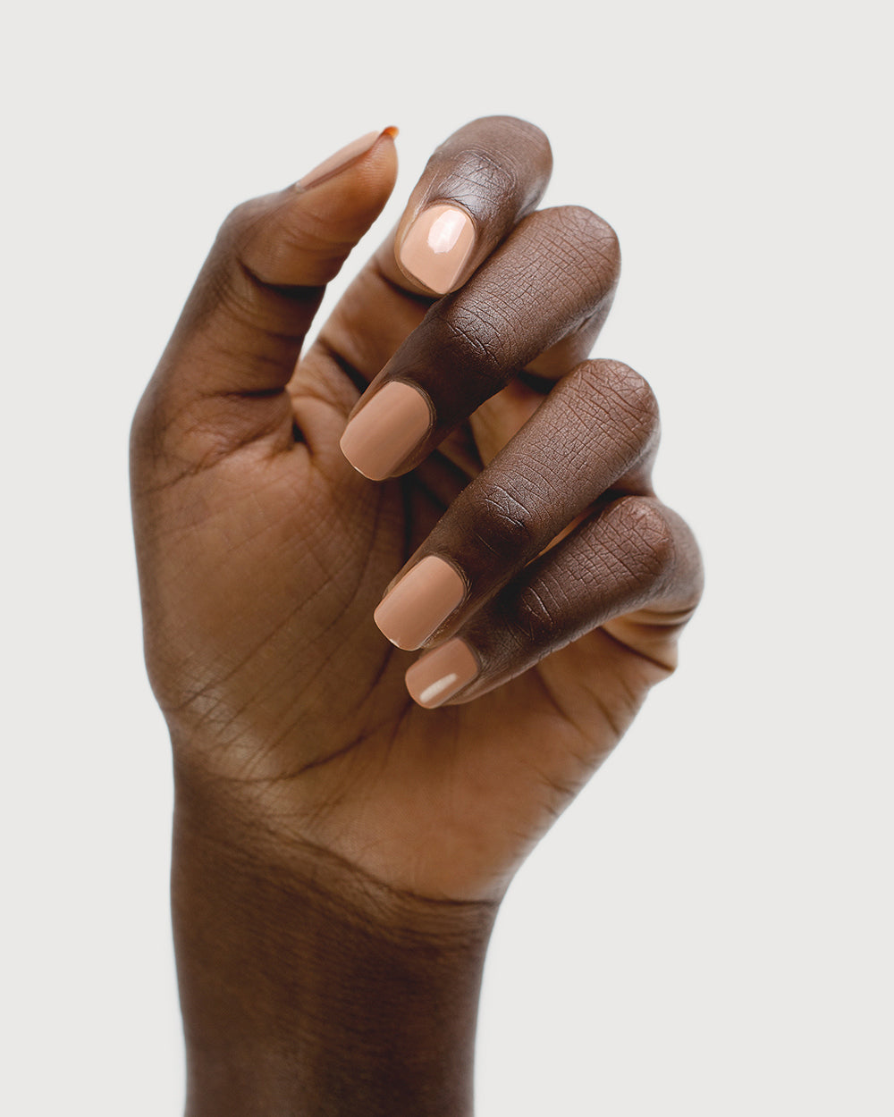 beige nude nail polish hand swatch on dark skin tone