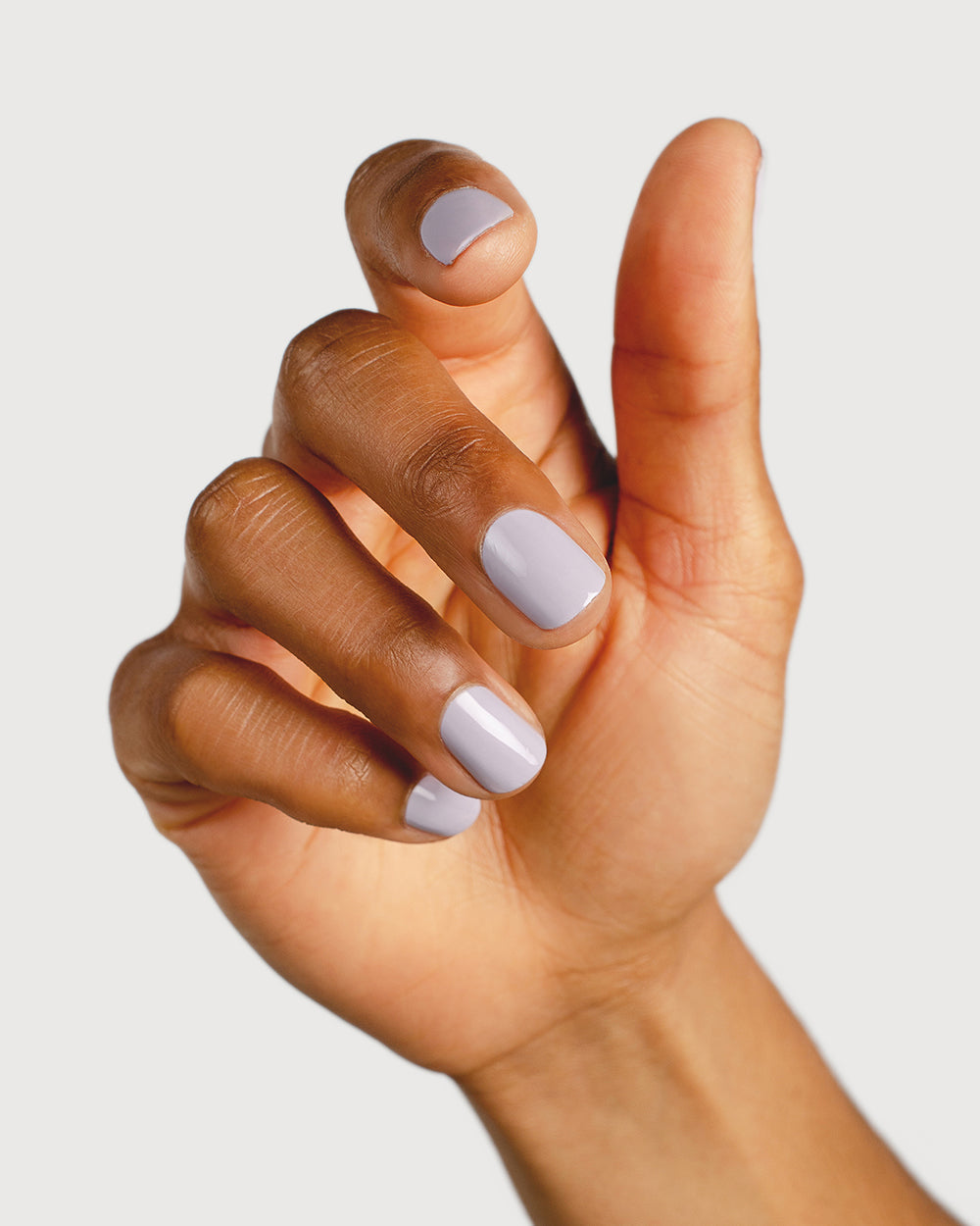 Pastel purple-grey nail polish hand swatch on medium skin tone 