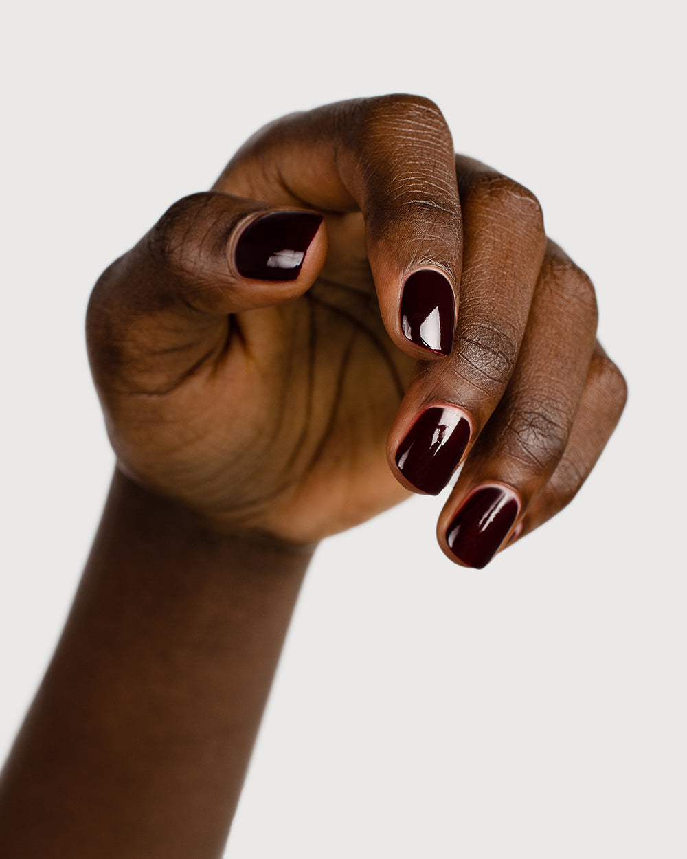 dark red nail polish hand swatch on dark skin tone