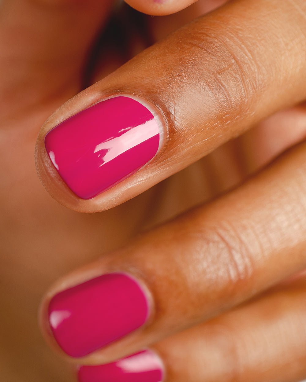 fuschia pink nail polish hand swatch on medium skin tone up close