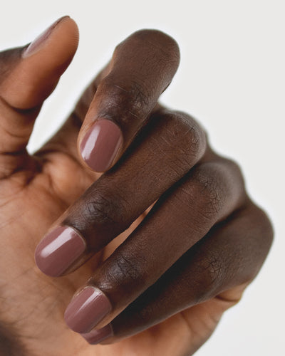 Dark skin hand wearing Grounded mylk chocolate crème nail polish by Sienna Byron Bay close-up