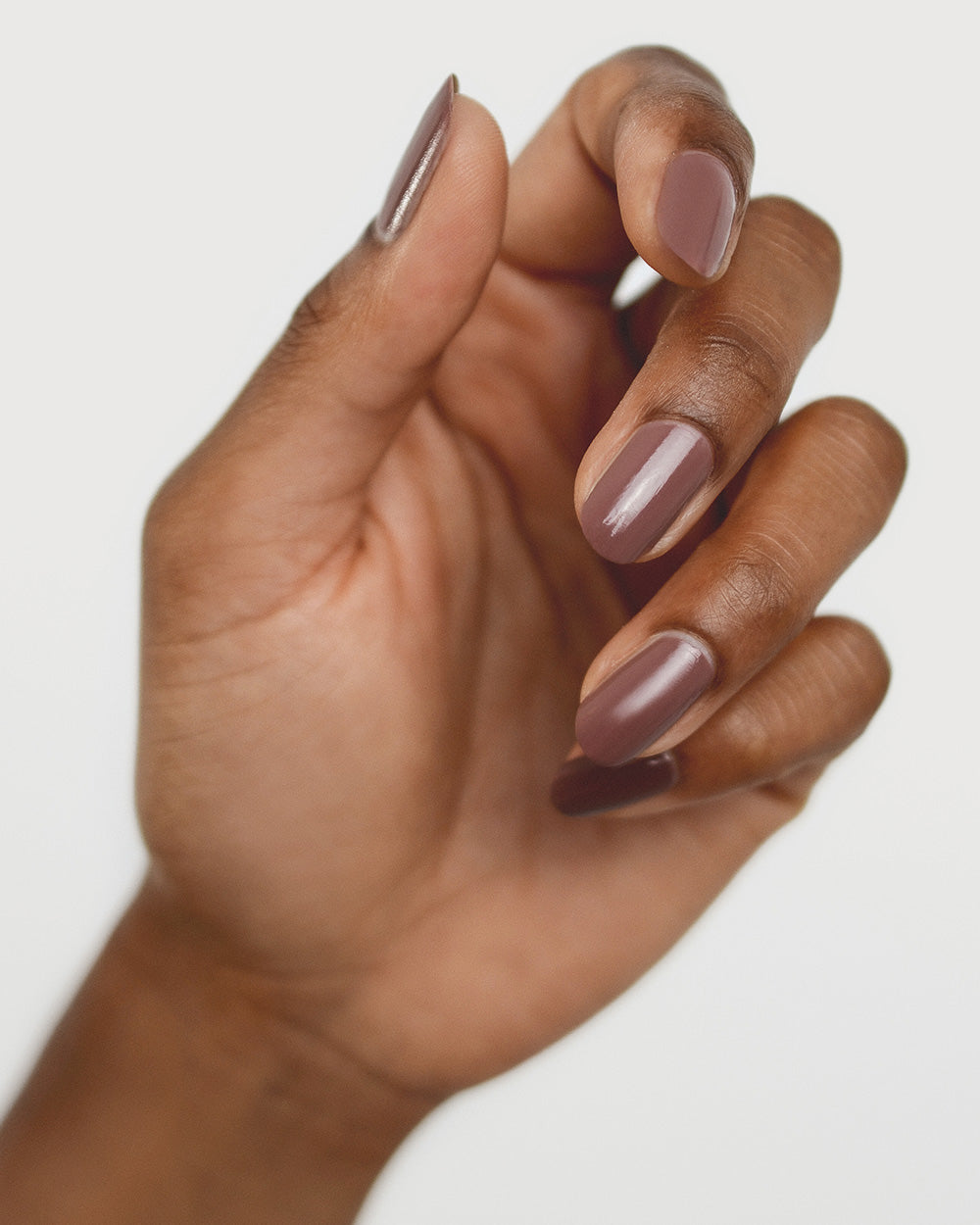 Medium tanned skin hand wearing Grounded mylk chocolate crème nail polish by Sienna Byron Bay