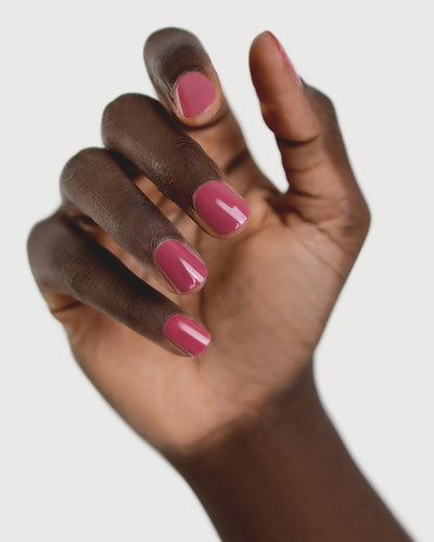 Dark skin hand wearing Heartspace raspberry sorbet nail polish by Sienna Byron Bay