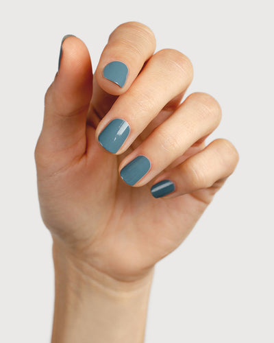 Mid grey-blue nail polish hand swatch on fair skin tone