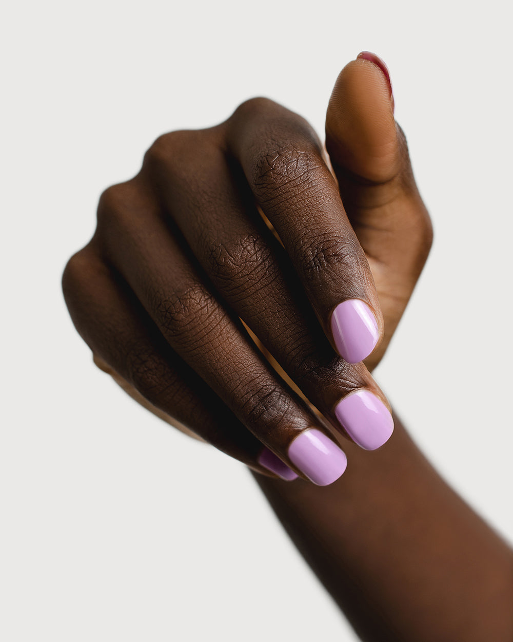 Mid-tone lilac nail polish hand swatch on dark skin tone