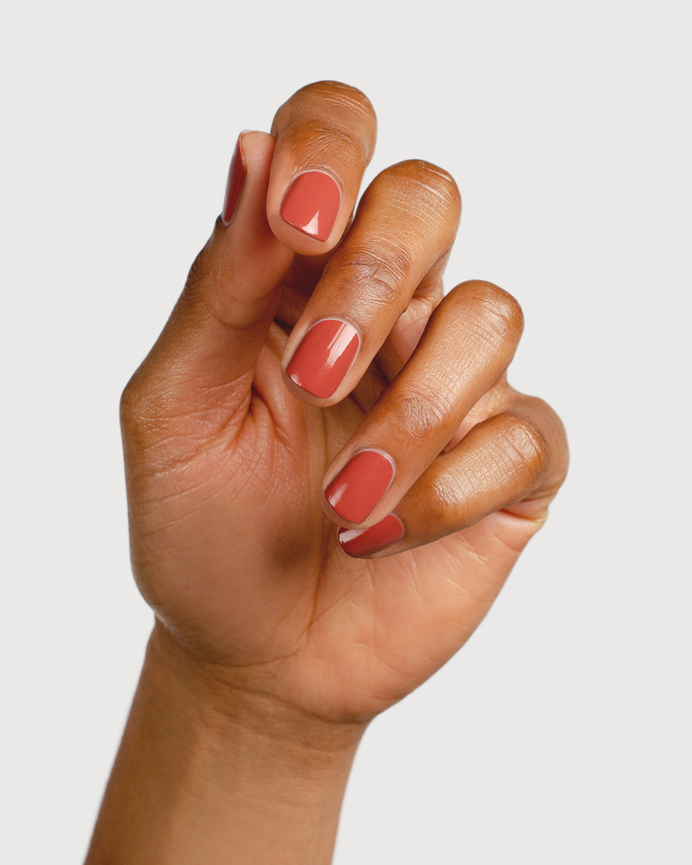 red brick nail polish hand swatch on medium skin tone