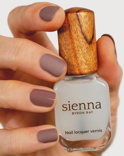 clear matte top coat nail polish hand swatch on medium skin tone holding sienna bottle up close