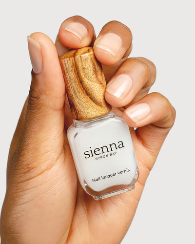 nail strengthener hand swatch on medium skin tone holding sienna bottle close up