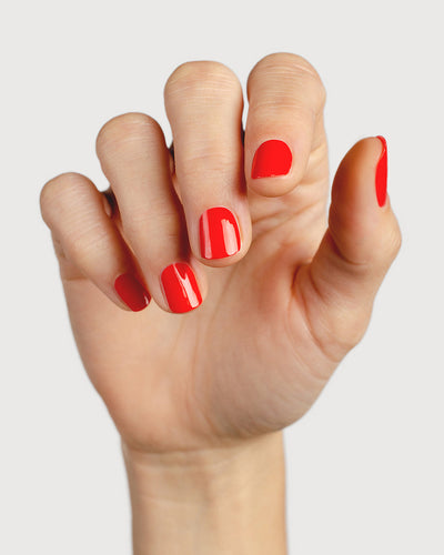 bright red nail polish hand swatch on fair skin tone