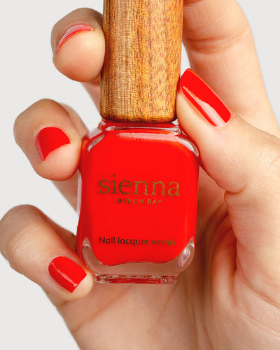 bright red nail polish hand swatch on fair skin tone holding sienna bottle