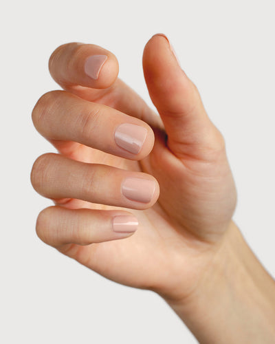 Soft neutral-pink nail polish hand swatch on fair skin tone