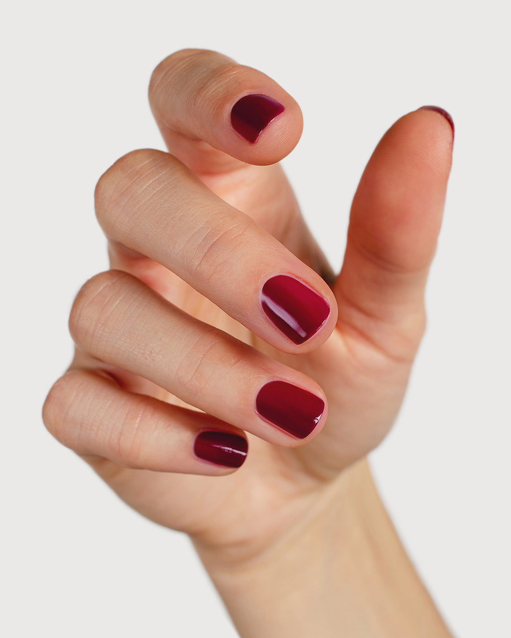 Plum red nail polish hand swatch on fair skin tone