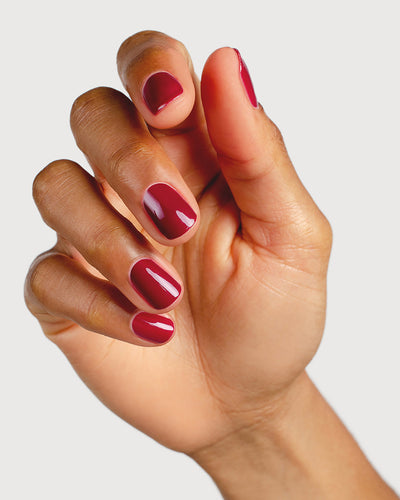 Plum red nail polish hand swatch on medium skin tone