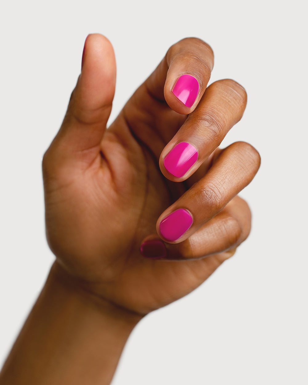 Bright magenta nail polish hand swatch on medium skin tone
