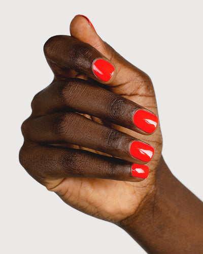 Warm strawberry red nail polish hand swatch on dark skin tone