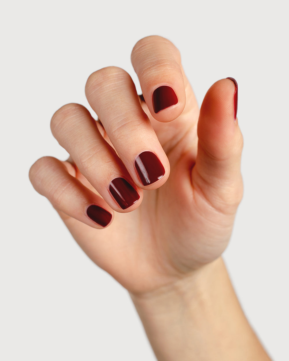 Organic mid-tone red nail polish hand swatch on fair skin tone