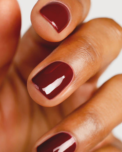 Organic mid-tone red nail polish hand swatch on medium skin tone up-close