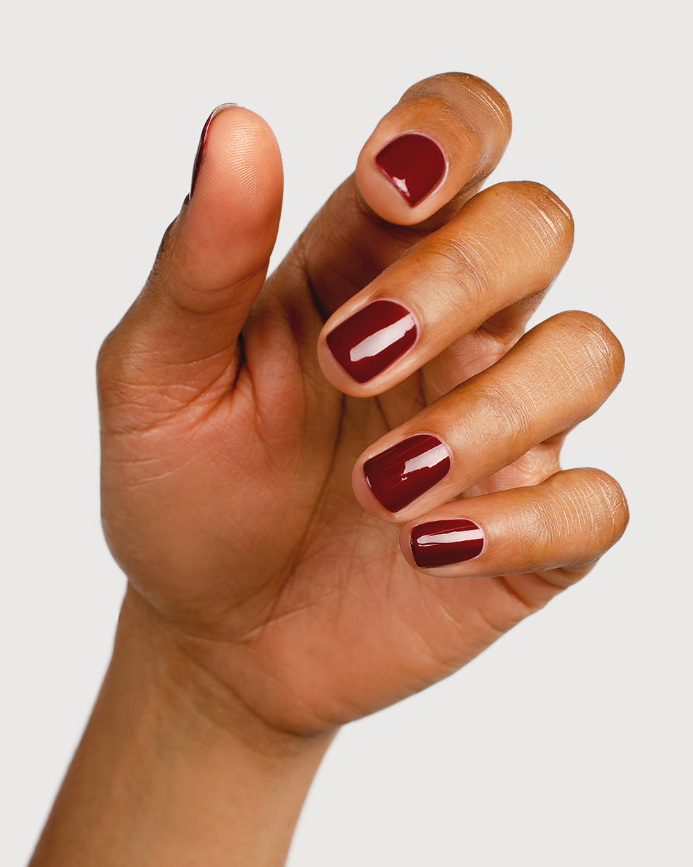 Organic mid-tone red nail polish hand swatch on medium skin tone