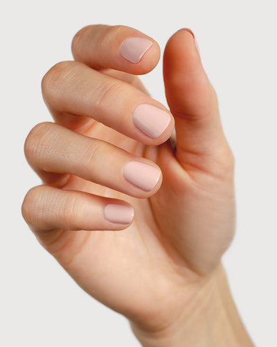 Light champagne pink nail polish hand swatch on fair skin tone