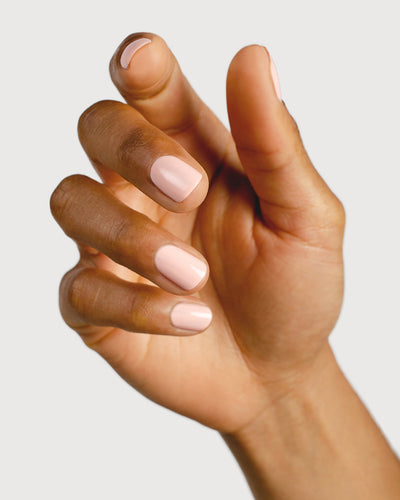 Light champagne pink nail polish hand swatch on medium skin tone