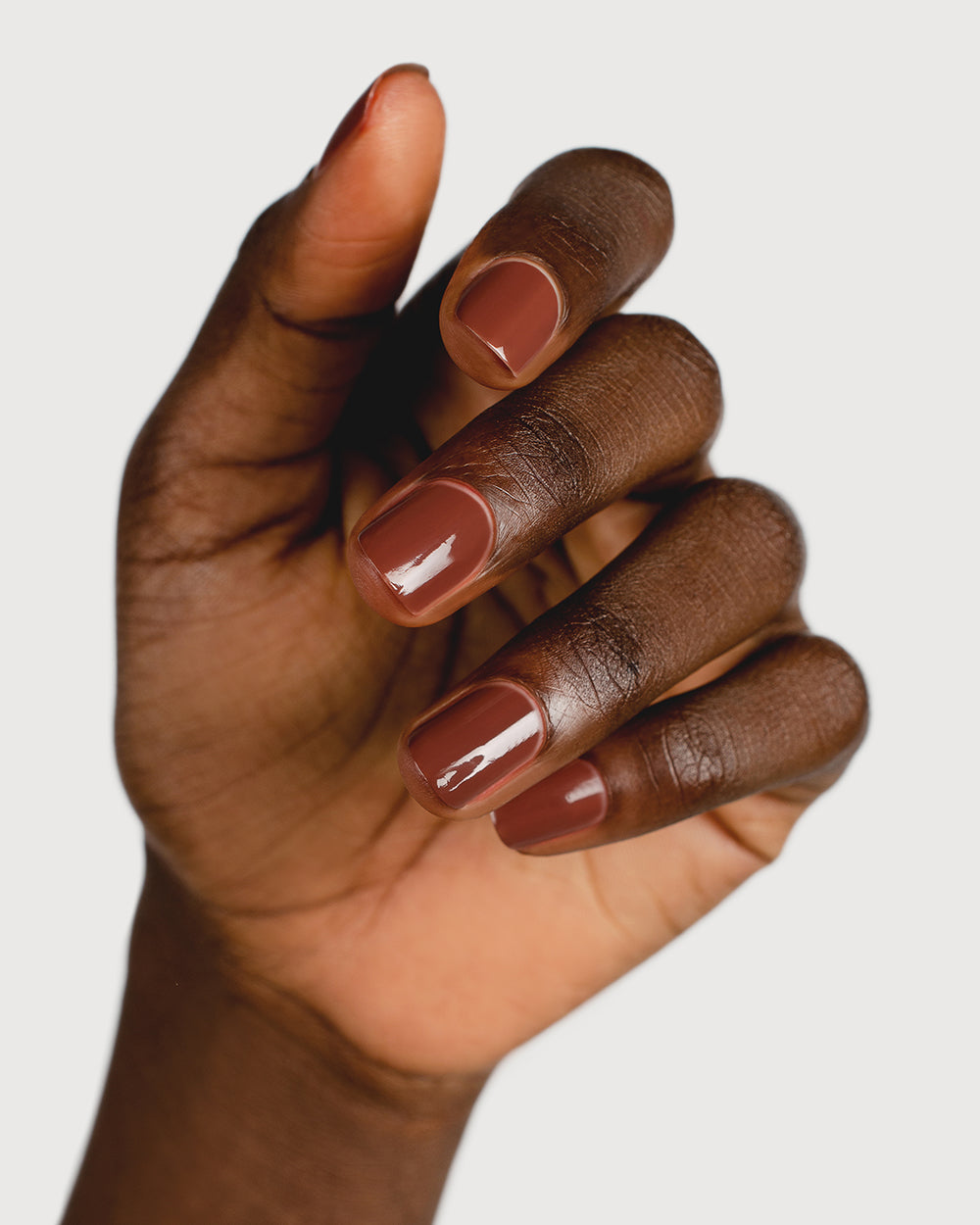 Deep burnt umber nail polish hand swatch on dark skin tone