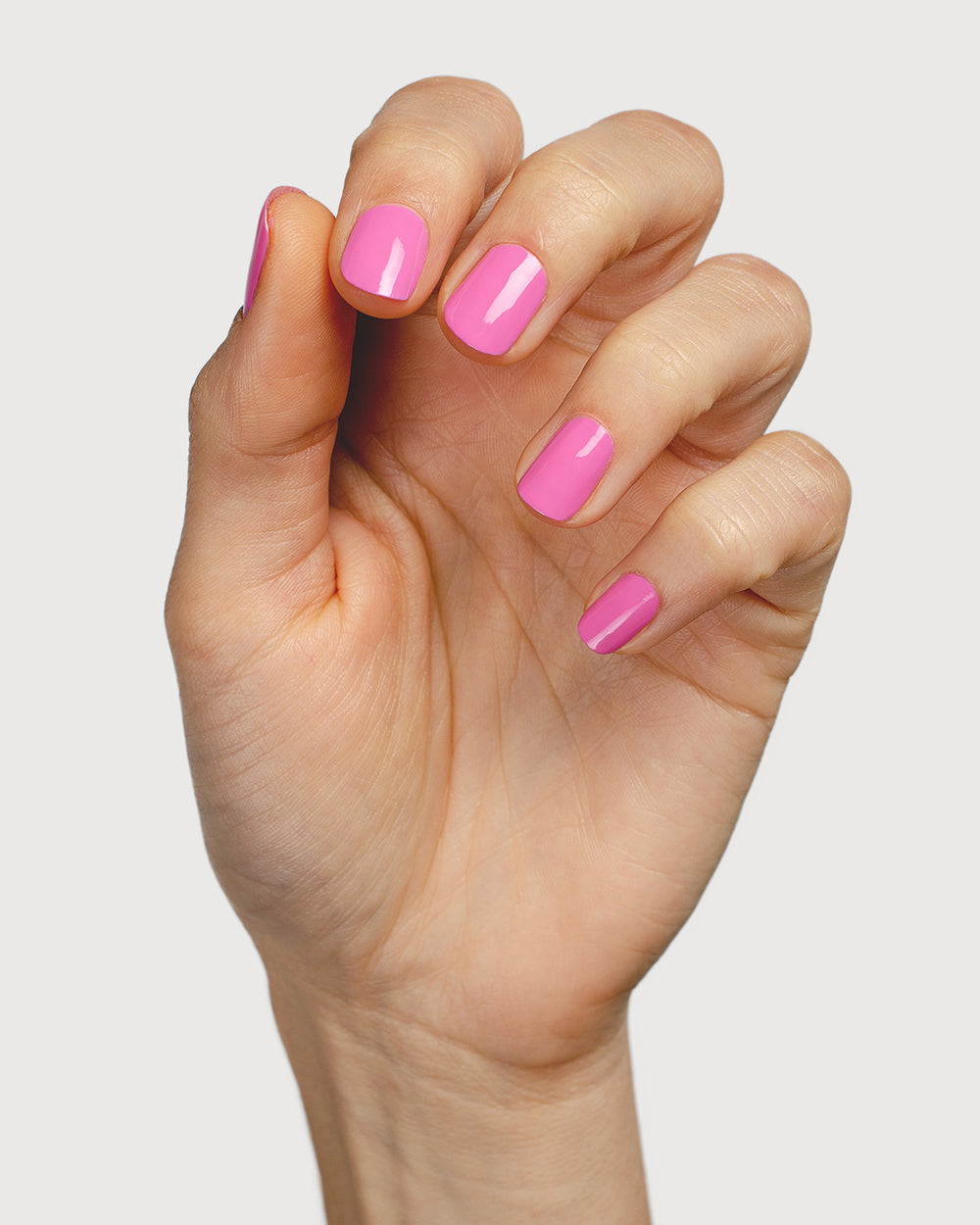 Bright mid-tone fuchsia nail polish hand swatch on fair skin tone