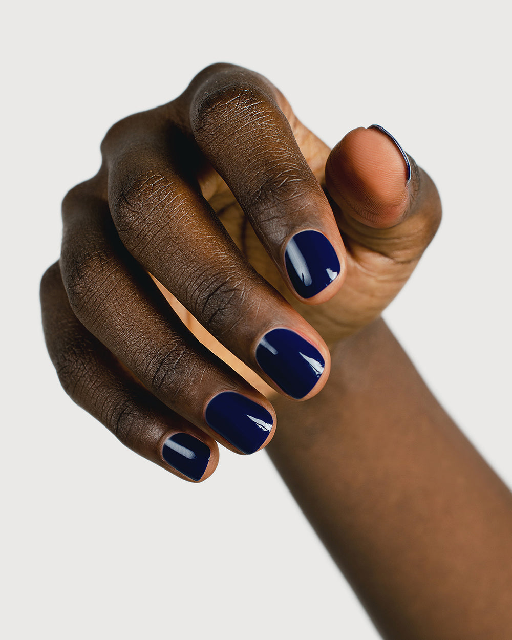 Classic navy blue nail polish hand swatch on dark skin tone