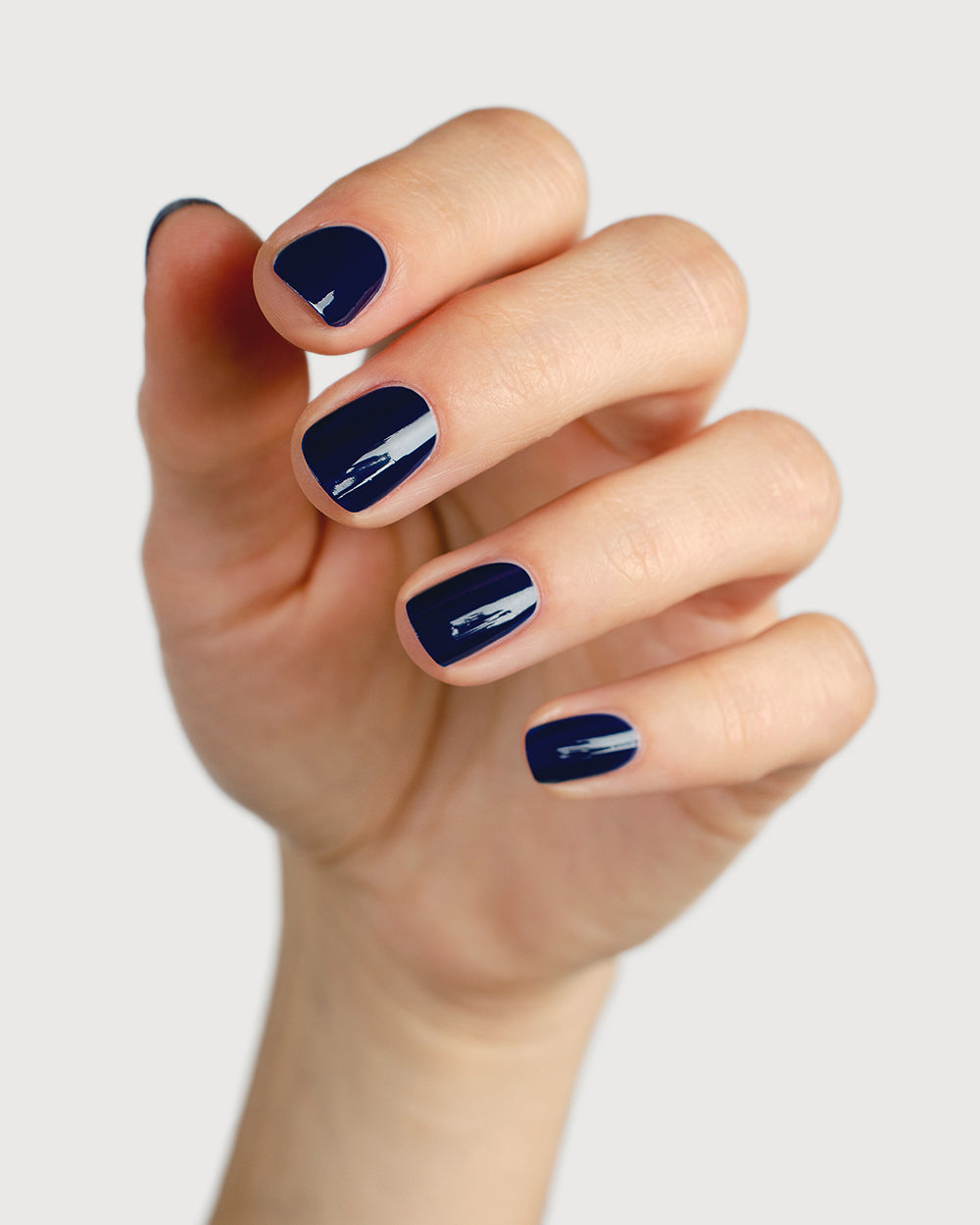 Classic navy blue nail polish hand swatch on fair skin tone