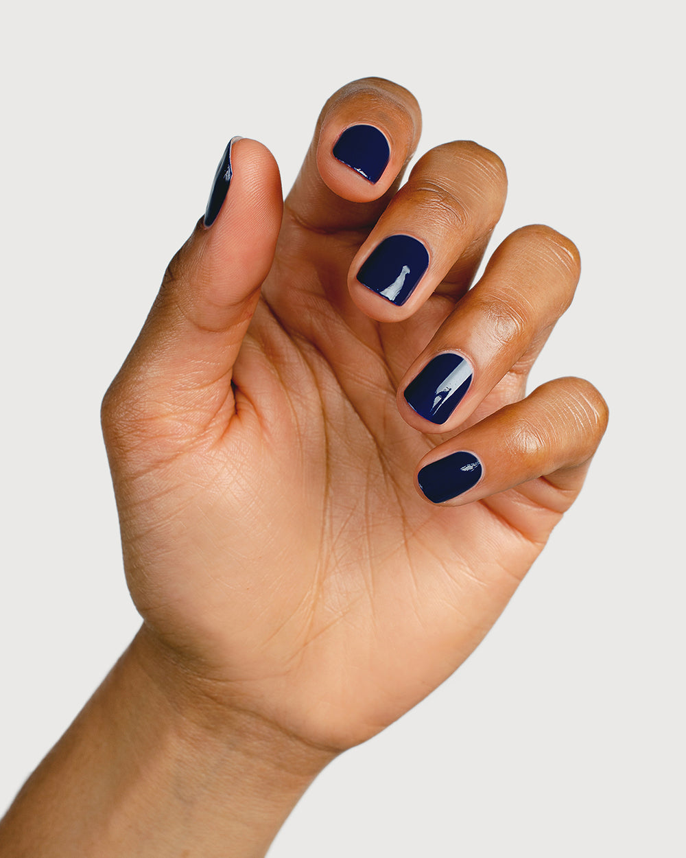 Classic navy blue nail polish hand swatch on medium skin tone