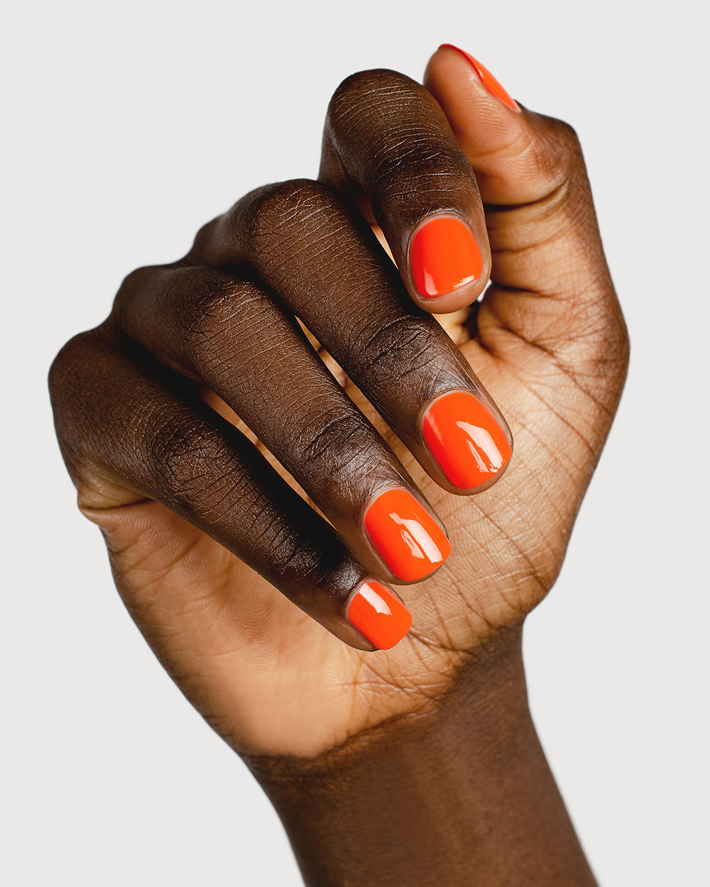 Tangerine nail polish hand swatch on dark skin tone