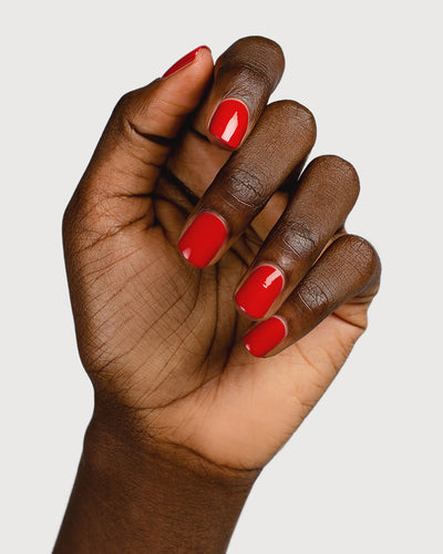 Classic red nail polish hand swatch on dark skin tone