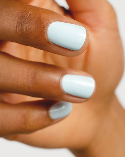 Pastel blue nail polish hand swatch on medium skin tone up close