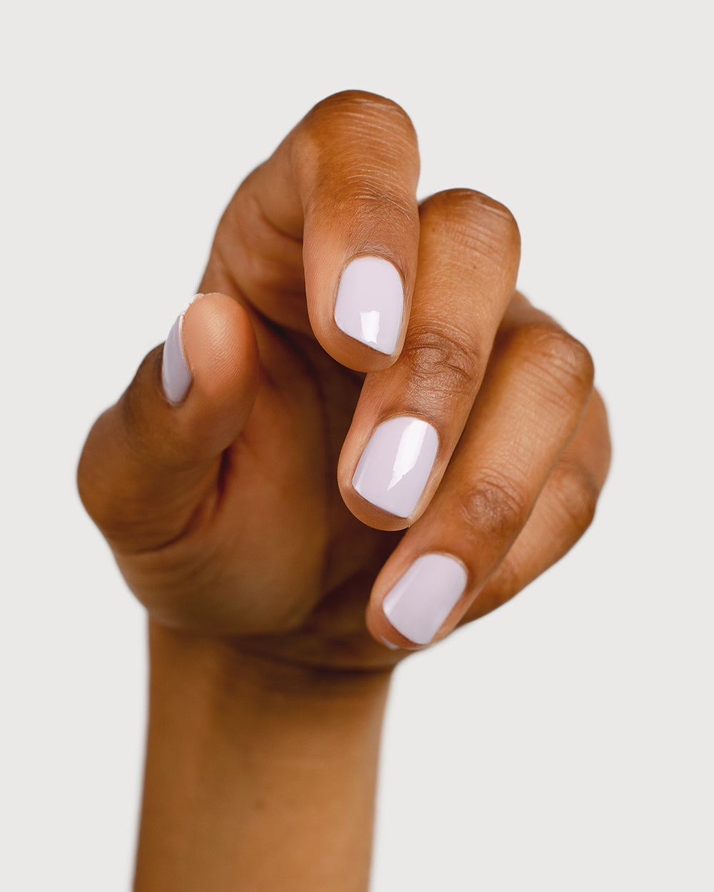 Light lilac pastel nail polish hand swatch on medium skin tone